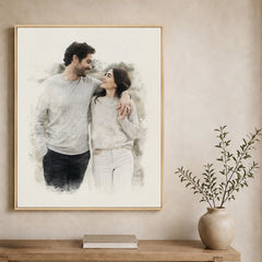 Custom couple watercolor portrait from a photo in a natural walnut frame above a light wood console table.